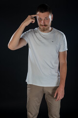 Young man pointing finger to his head while posing on black background studio. Isolated