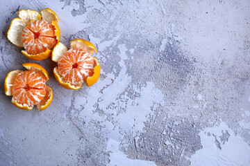 Three tangerines in the remaining peel on a light gray background. Side space for design