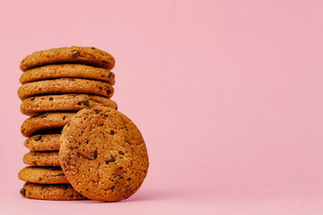 Stacked chocolate chip cookies against pink background