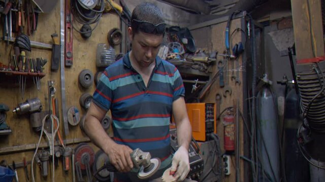 A locksmith processes a wooden part using a grinder 