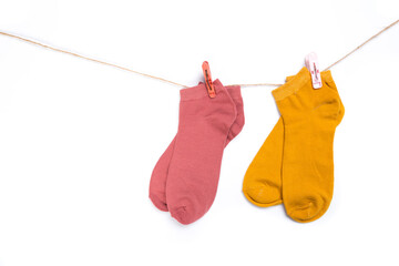 several colored socks hanging on a rope with clothespins isolated on white background