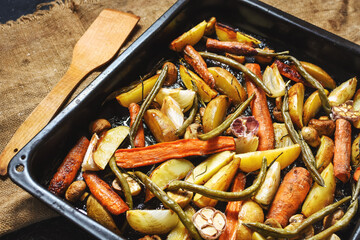 Baked vegetables on baking sheet. Potatoes, carrot, mushrooms and onions