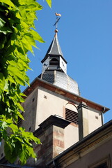 Fototapeta na wymiar Ville de Sarreguemines, clocher ensoleillé d'une église de la ville, verdure en premier plan, département de la Moselle, France