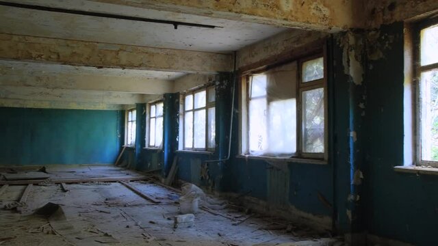 an abandoned building with large Windows, blue paint falling off the walls, garbage everywhere. horrors