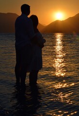 Silhouettes of girls and boys against the background of the sunrise in the sea. Sunrise in Icmeler.
