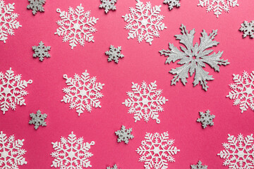 Christmas holidays composition with silver christmas decorations and snowflakes on pink background with copy space for your text