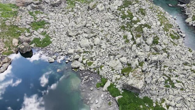 Aerial view of small mountain lake with water reflaction in the Alps. Drone flight footage 4K UHD
