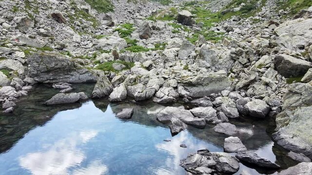 Aerial view of small mountain lake with water reflaction in the Alps. Drone flight footage 4K UHD