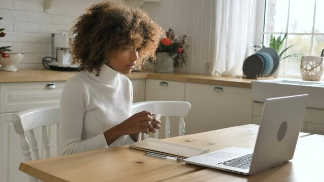 Dark skinned student with kinky hair puts on earpods opens exercise book and prepares for distant lesson closeup slow motion