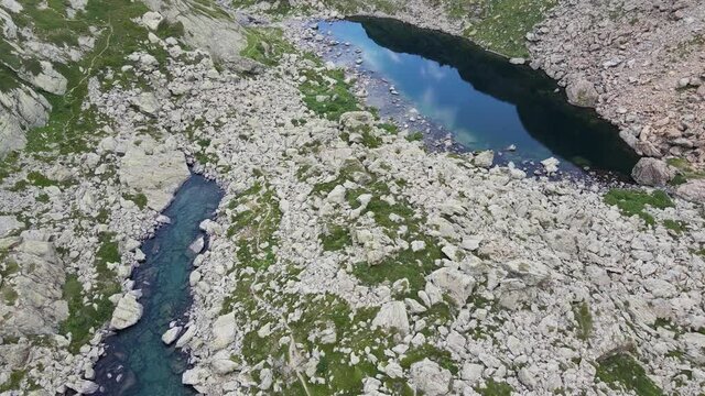 Aerial view of small mountain lake with water reflaction in the Alps. Drone flight footage 4K UHD