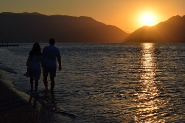 Silhouettes of girls and boys holding hands against the background of the sunrise in the sea. Sunrise in Icmeler.