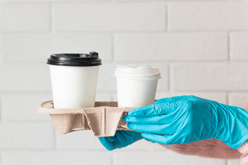 Girl hold takeaway coffee in holder in the blue medical gloves. Safety and protection in epidemic...