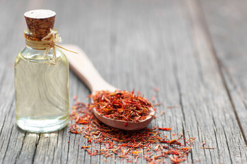 Glass bottle of saffron essential oil on wooden rustic background, spice or herb oil concept,...