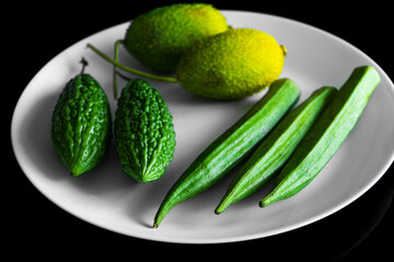 green vegetables in white plate on black background flat lay