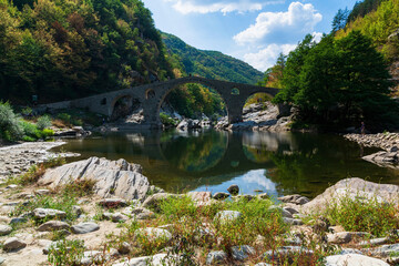 Fototapeta na wymiar Devil's Bridge - an ancient stone bridge over the Arda River near Ardino Town, Bulgaria, Europe