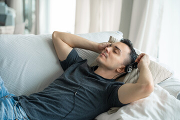 the guy enjoys the music while lying on the couch with headphones. Relaxation with music