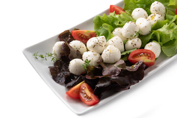 Vassoio di insalata fresca di mozzarelline e verdure con olio extravergine di oliva e origano 