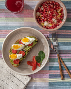 Tostada de aguacate con bol de fruta y zumo de ar&aacute;ndanos