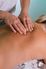 From above crop hands of professional therapist doing massage of female back in wellness salon