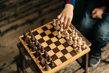Close-up of hand of unrecognizable child making his move in chess game. Kid boy playing chess,...