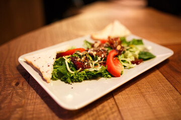 Serve vegetable salad in a white plate. Cozy wooden pub