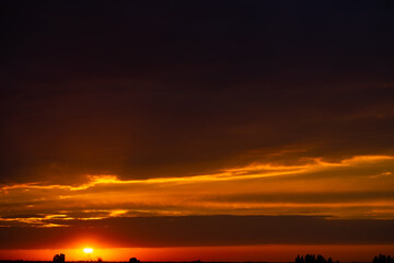 Heavy cloudy sky at sunset. Orange line of light between black clouds. A landscape of beautiful nature