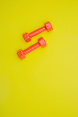 Red dumbbells for sports on a yellow background.