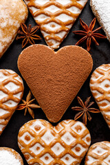 Christmas heart-shaped gingerbread cookies on a dark background close up view. Traditional festive dessert
