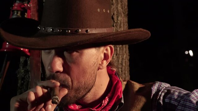 Cowboy with a cigar in the forest at night. Life in the wild west of America. 4K
