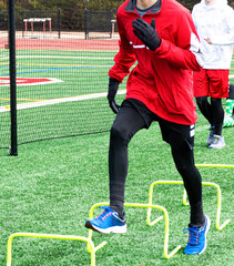Runner running over mini hurdles on green turf field