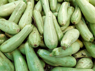 Green courgette. An elongated green vegetable on a shelf in the supermarket. Freshly harvested green courgette. Summer courgette. Background. Texture. View from above.