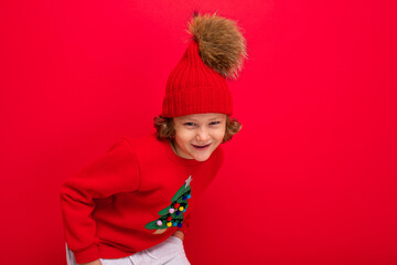 boy model on a red background, portrait of a cool blonde with curls in a sweater with a Christmas tree