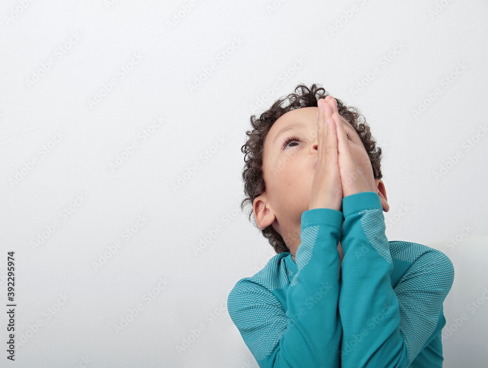 Wall mural boy praying to god with hands together stock photo