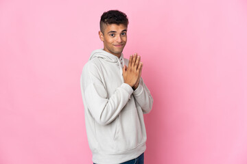Young Brazilian man isolated on pink background scheming something