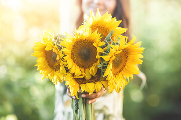 Beautiful lady holding sunflower. Bouquet of flowers in the summer.
