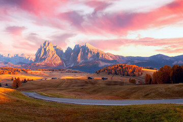 Mountain meadow and wood house Alpe di Siusi or Seiser Alm in the background Langkofel mountain range at beautiful sunset with Province of Bolzano, South Tyrol in Dolomites