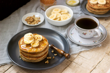 Pancakes with banana, nuts and honey, served with tea. Rustic style.