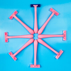 A pink razor with a blue cassette surrounded by pink razors on a light blue background.