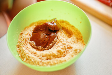Mixing ingredients for pie. Boiled condensed milk with ground cookies. The base for cake. Preparation of biscuits. Baking background. 