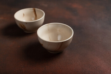 Two light handmade cups on a brown background