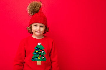 boy model on a red background, portrait of a cool blonde with curls in a sweater with a Christmas tree