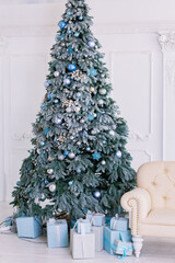 Fototapeta premium Christmas tree is decorated with blue balls in a classic white interior