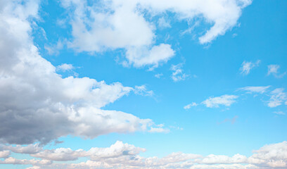 Blue sky and white clouds background - Pillowy clouds cover a blue sky in the background