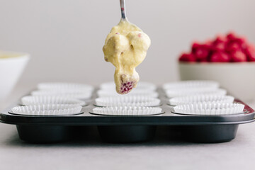 Dropping raspberry fruit muffin cake mix into muffin liners in t