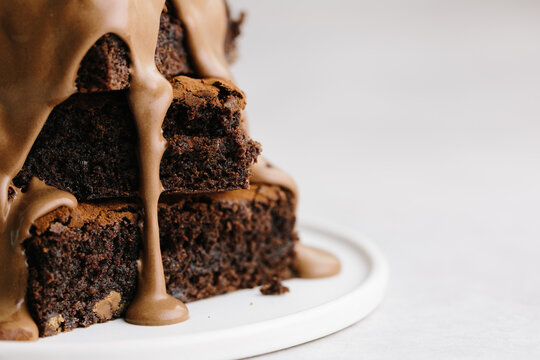 Close up of chocolate ganache sauce poured over brownie stack