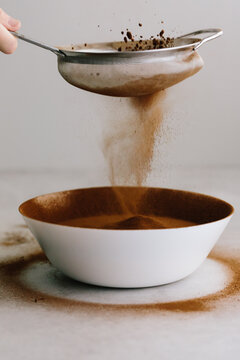 Sieve sifting cocoa powder into a mixing bowl