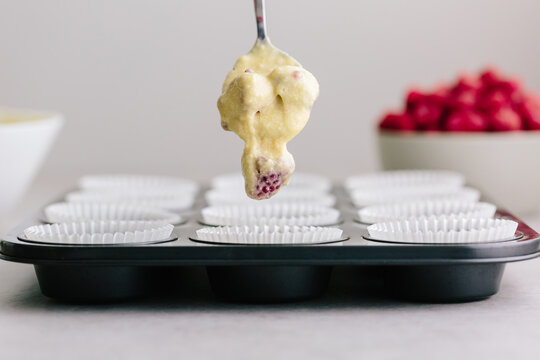 Dropping raspberry fruit muffin cake mix into muffin liners in t
