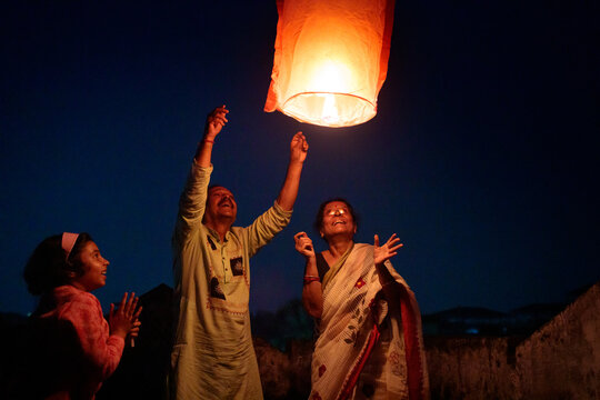 Senior couple releasing sky lantern at evening with their granddaughter ,having fun