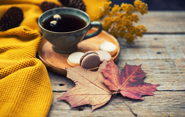 Naklejka na ściany i meble Autumn, fall leaves, hot steaming cup of tea and a warm scarf on rustic wooden table background. Seasonal, morning tea, sunday relaxing on the garden and still life.