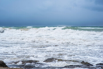 Autumn sea landscape. Rough sea with waves during autumn stormy weather. Dark heavy clouds in the sky. Dark and dramatic storm clouds background.